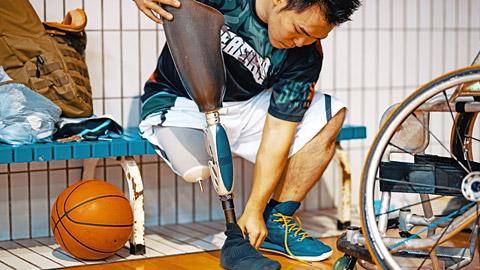 Male basketball player preparing to put on a prosthetic leg