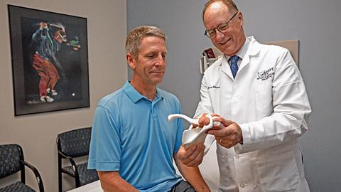 Doctor showing a patient a model of a joint