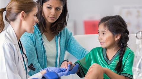 Doctor examining a young girl with sports related injuries